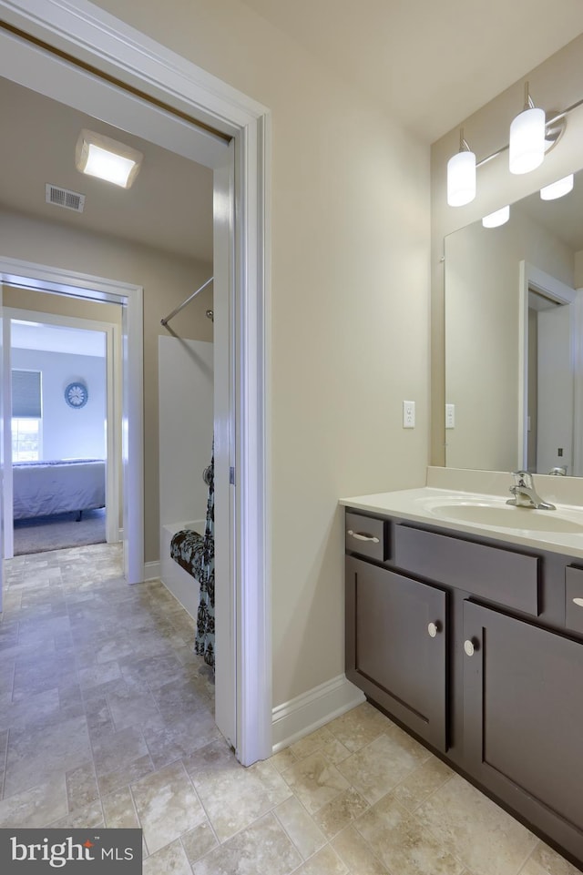 bathroom featuring stone finish flooring, baseboards, vanity, and visible vents