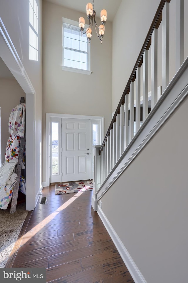 foyer featuring visible vents, a notable chandelier, a high ceiling, stairway, and hardwood / wood-style floors