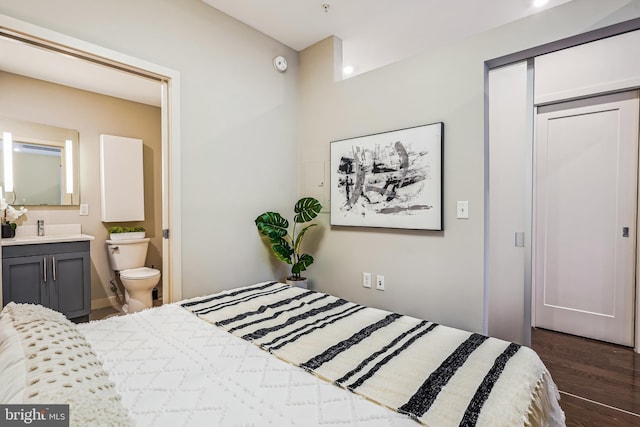 bedroom with ensuite bathroom, dark hardwood / wood-style floors, and sink