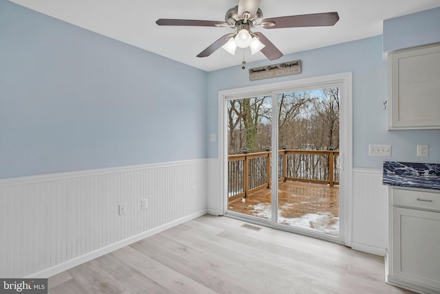 unfurnished dining area with ceiling fan and light wood-type flooring