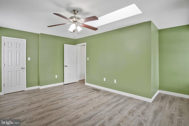 unfurnished bedroom featuring a skylight, ceiling fan, and light wood-type flooring