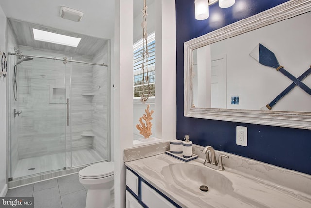 bathroom featuring a skylight, tile patterned flooring, vanity, toilet, and a shower with door