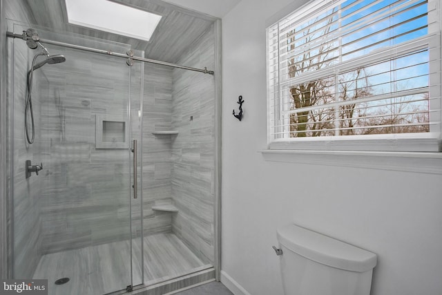 bathroom with a skylight, toilet, and walk in shower