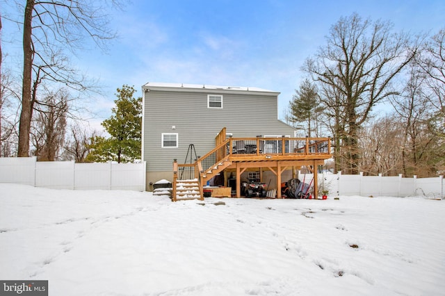 snow covered back of property featuring a wooden deck