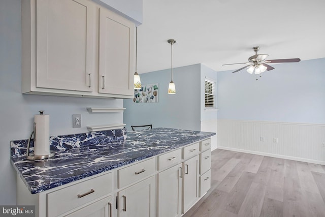 kitchen featuring pendant lighting, dark stone counters, ceiling fan, and light wood-type flooring