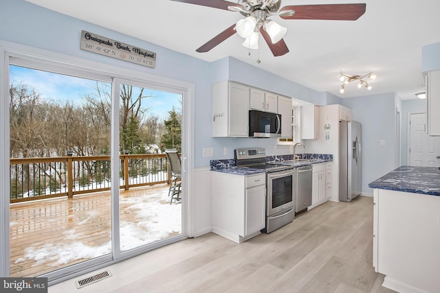 kitchen with sink, white cabinetry, appliances with stainless steel finishes, ceiling fan, and light hardwood / wood-style floors