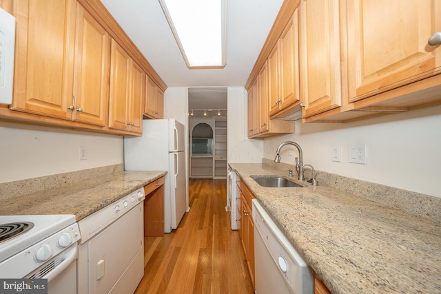 kitchen with sink, white appliances, light stone countertops, light hardwood / wood-style floors, and light brown cabinetry