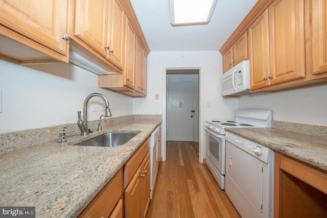 kitchen with sink, white appliances, light hardwood / wood-style flooring, and light stone countertops