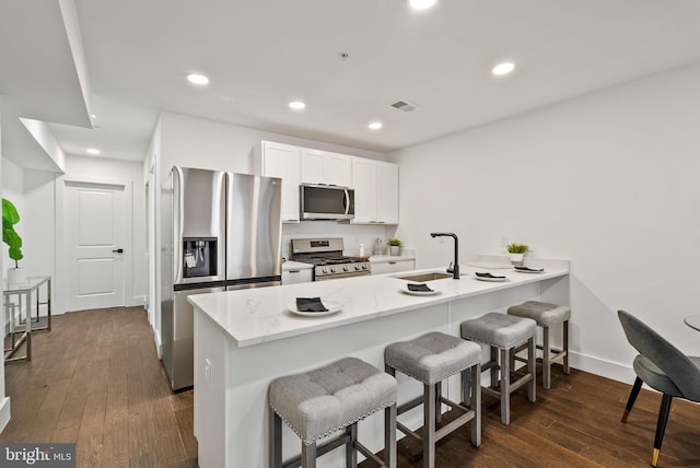 kitchen featuring stainless steel appliances, sink, a breakfast bar area, and white cabinets