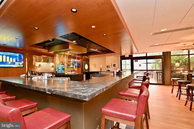 bar with a dry bar, light wood finished floors, wooden ceiling, a wall of windows, and recessed lighting