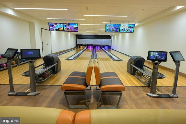 interior space with hardwood / wood-style flooring, a bowling alley, and a drop ceiling