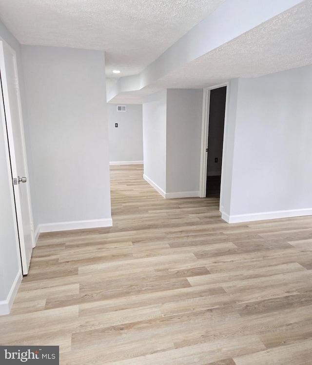 spare room featuring light hardwood / wood-style floors and a textured ceiling