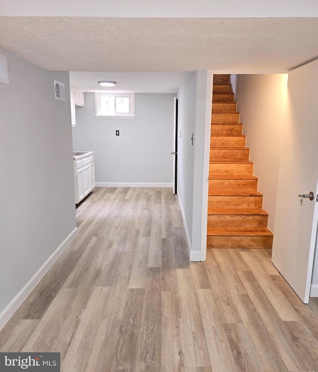 hallway featuring a textured ceiling and light hardwood / wood-style floors