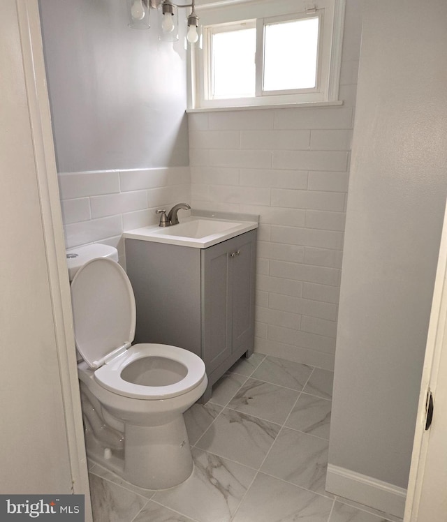 bathroom with vanity, tile walls, and toilet