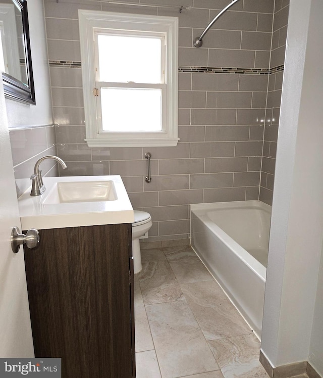 full bathroom featuring vanity, tile walls, toilet, and washtub / shower combination