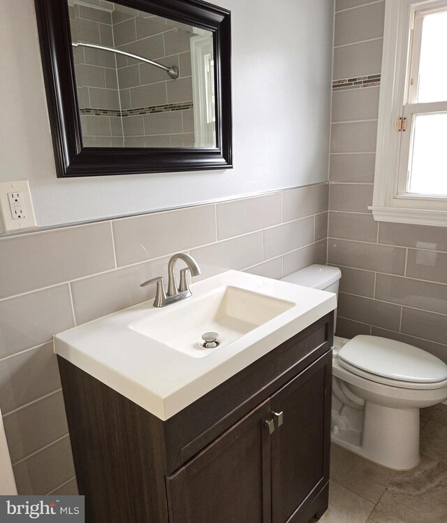 bathroom with vanity, tile patterned floors, toilet, and tile walls