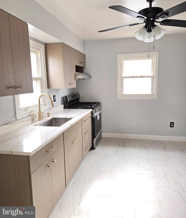 kitchen with sink, stainless steel gas range, wall chimney range hood, and ceiling fan