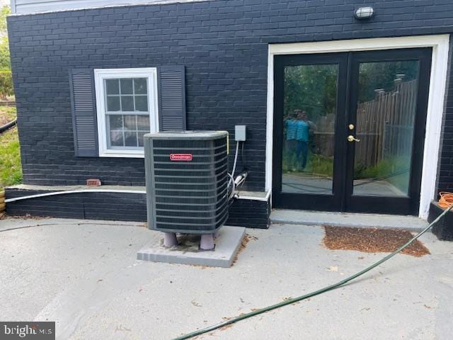 entrance to property with brick siding, french doors, and central AC