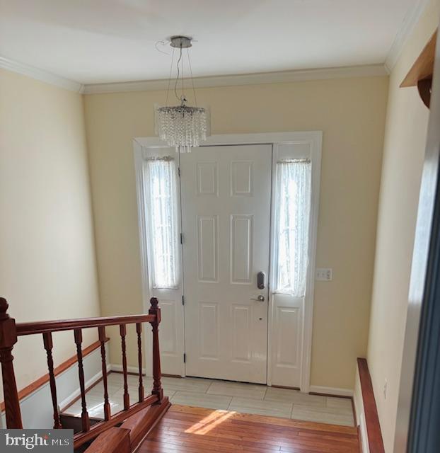 entrance foyer featuring light wood-type flooring, baseboards, and crown molding