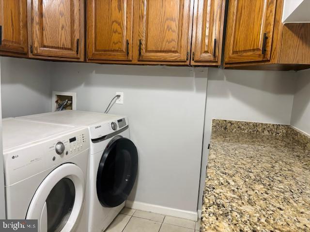 laundry area with baseboards, cabinet space, washer and clothes dryer, and light tile patterned flooring