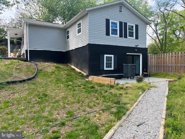 view of side of property with central air condition unit, fence, a yard, and a patio