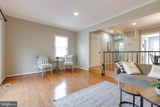 living area featuring visible vents, crown molding, and baseboards