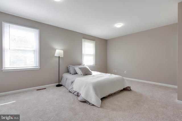 carpeted bedroom featuring baseboards and visible vents