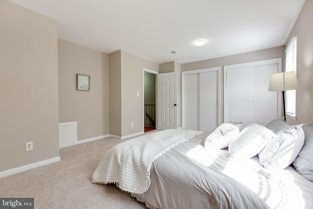 bedroom with carpet, multiple closets, and baseboards