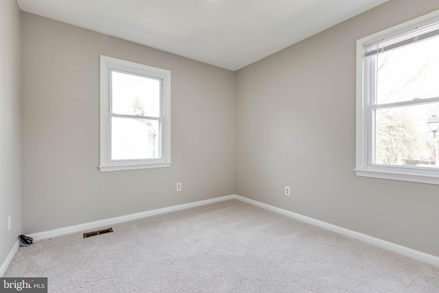 unfurnished room with plenty of natural light, baseboards, visible vents, and carpet