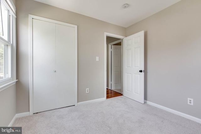 unfurnished bedroom featuring baseboards, carpet flooring, and a closet