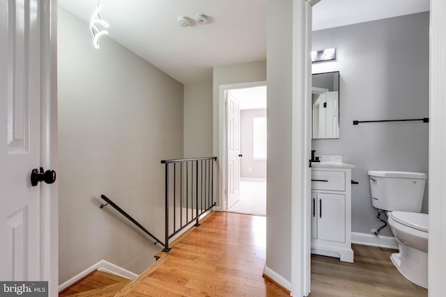 bathroom with baseboards, wood finished floors, vanity, and toilet