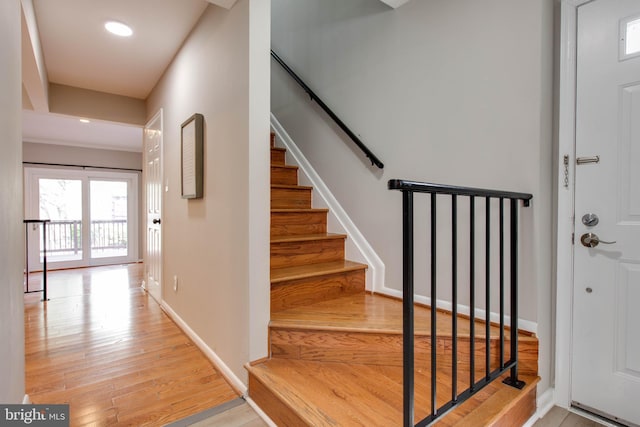 stairs with baseboards, wood finished floors, and recessed lighting