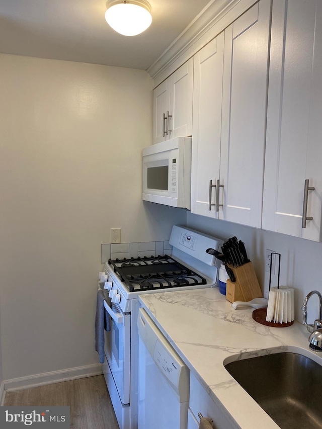 kitchen with light stone counters, white appliances, sink, and white cabinets