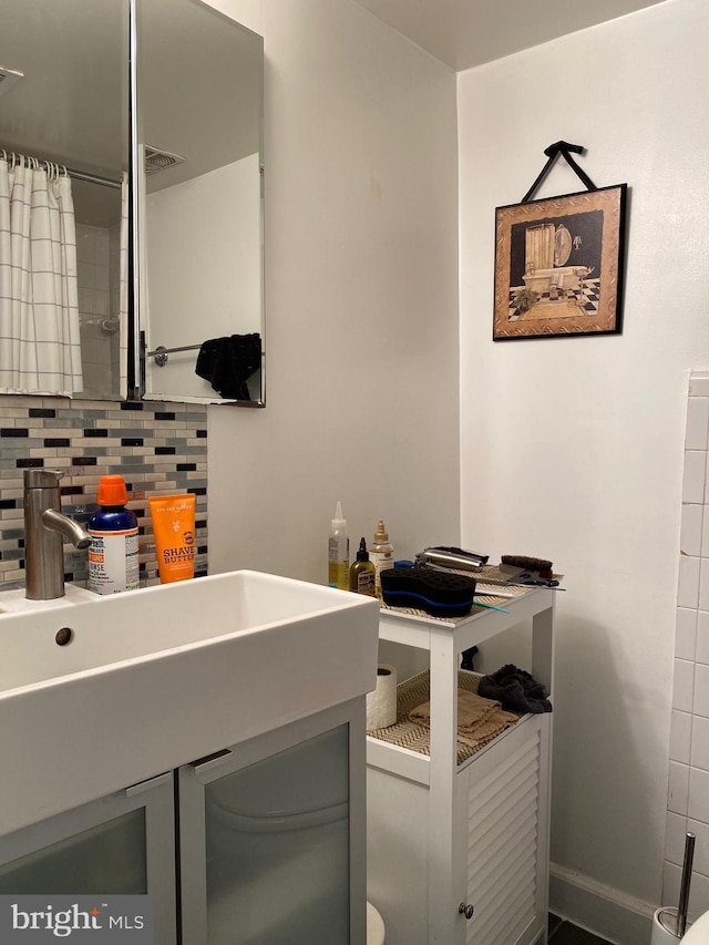 bathroom featuring vanity, backsplash, and toilet