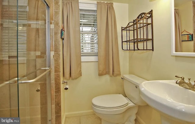 bathroom with a shower with door, sink, tile patterned floors, and toilet