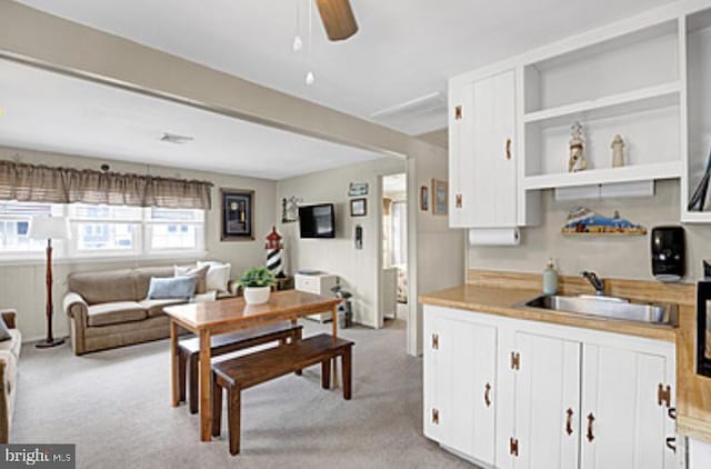 7 E 19th St, Long Beach Township, NJ 08008 - kitchen featuring white cabinetry, light carpet, ceiling fan, and a sink