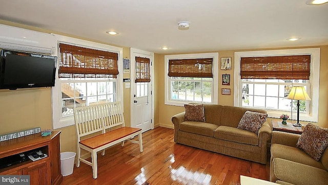 living room featuring hardwood / wood-style floors, a wall mounted air conditioner, and plenty of natural light