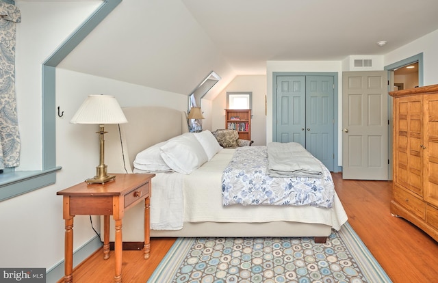 bedroom featuring vaulted ceiling, a closet, and light wood-type flooring