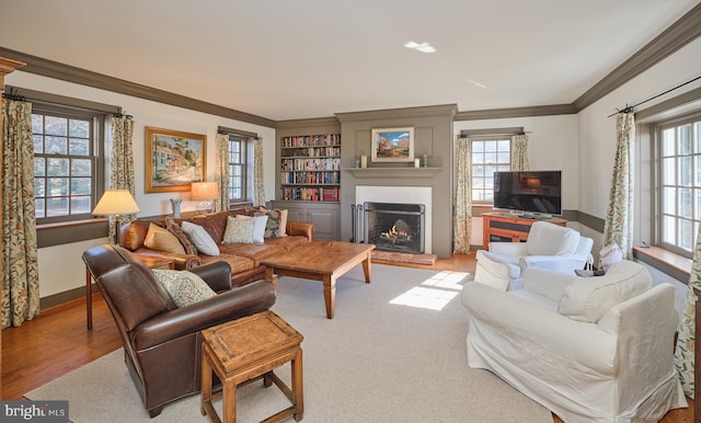 living room with ornamental molding, a wealth of natural light, and light hardwood / wood-style floors