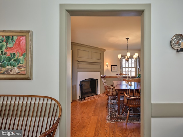 dining space featuring a notable chandelier, hardwood / wood-style flooring, and a large fireplace