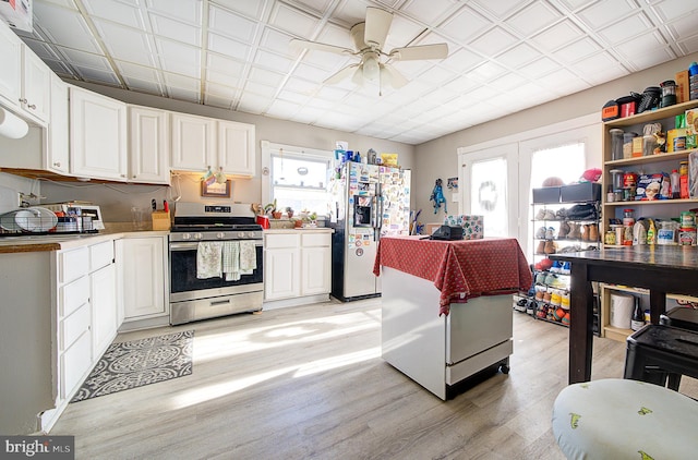 kitchen with ceiling fan, white cabinetry, white refrigerator with ice dispenser, gas stove, and light wood-type flooring