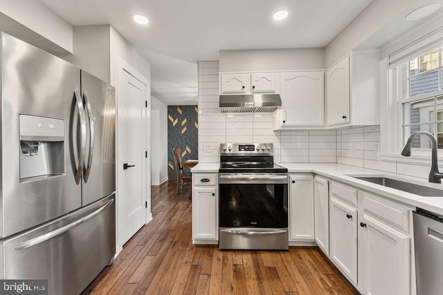 kitchen featuring a sink, light countertops, range hood, white cabinets, and stainless steel appliances