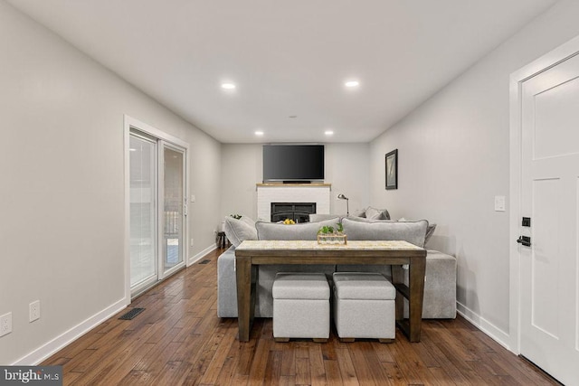 living area with dark wood finished floors, baseboards, a brick fireplace, and visible vents