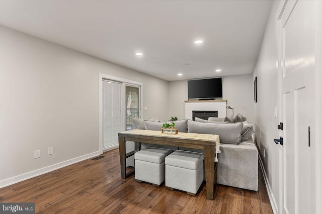 living room featuring recessed lighting, dark wood-style floors, visible vents, a brick fireplace, and baseboards