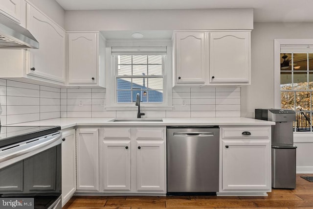 kitchen with light countertops, stainless steel appliances, a sink, white cabinetry, and under cabinet range hood