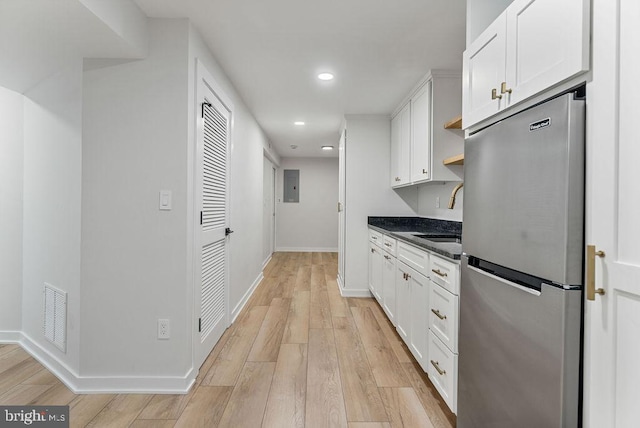 kitchen with freestanding refrigerator, visible vents, a sink, open shelves, and white cabinets