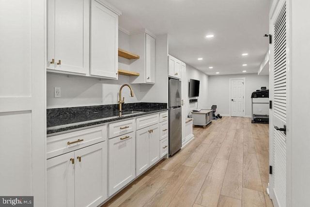 kitchen with dark stone countertops, freestanding refrigerator, white cabinets, open shelves, and light wood-type flooring