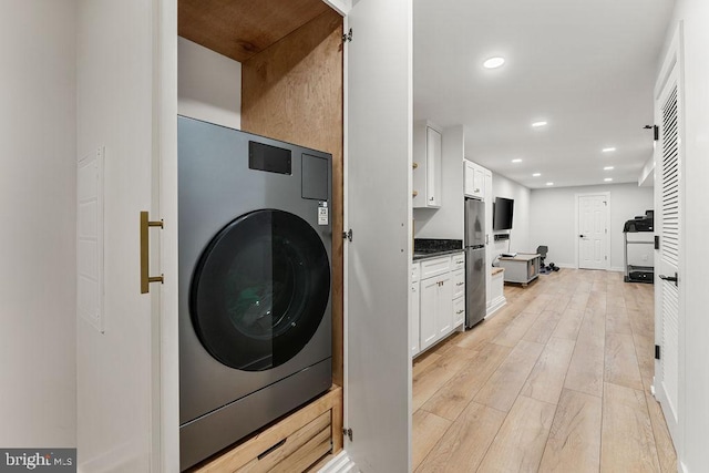 clothes washing area featuring baseboards, washer / clothes dryer, light wood finished floors, laundry area, and recessed lighting