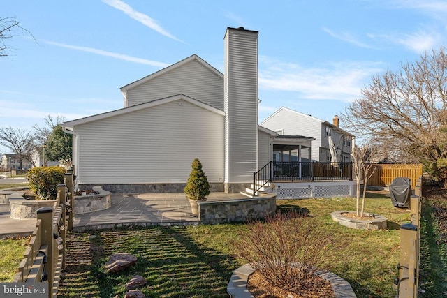 view of side of home with a chimney, a yard, and fence