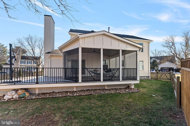 rear view of property with a lawn, a sunroom, board and batten siding, a fenced backyard, and a chimney